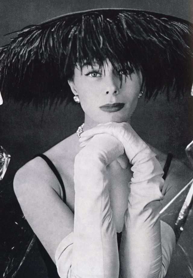 Bettina, the "Rive Droite beauty," posing for Jacques Fath perfumes, wearing hat covered with ostrich feathers, April 1953