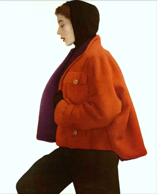 Bettina in brick-red wool jacket lined in purple, worn over black hooded sweater and black gabardine pants, by Manguin, 1950