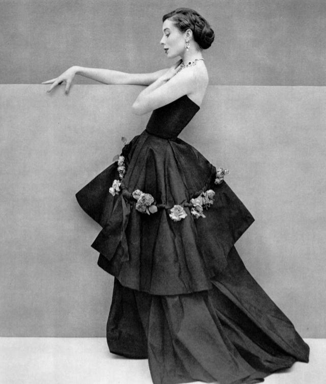 Bettina in graceful black silk evening gown, the tunic is decorated with band of roses, by Grès, 1950