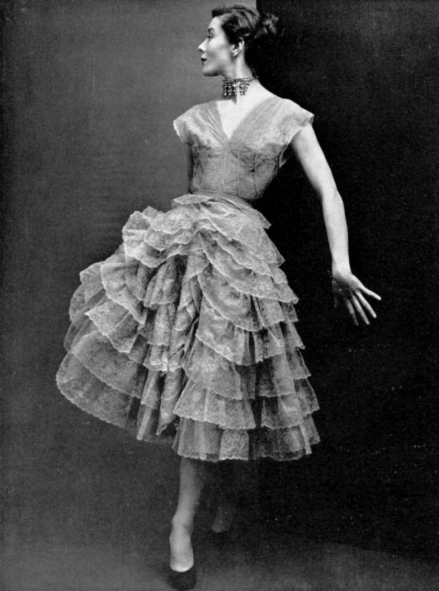 Bettina in gray lace dress, skirt is wound round with frilly lace ruffles, by Robert Piguet, 1950