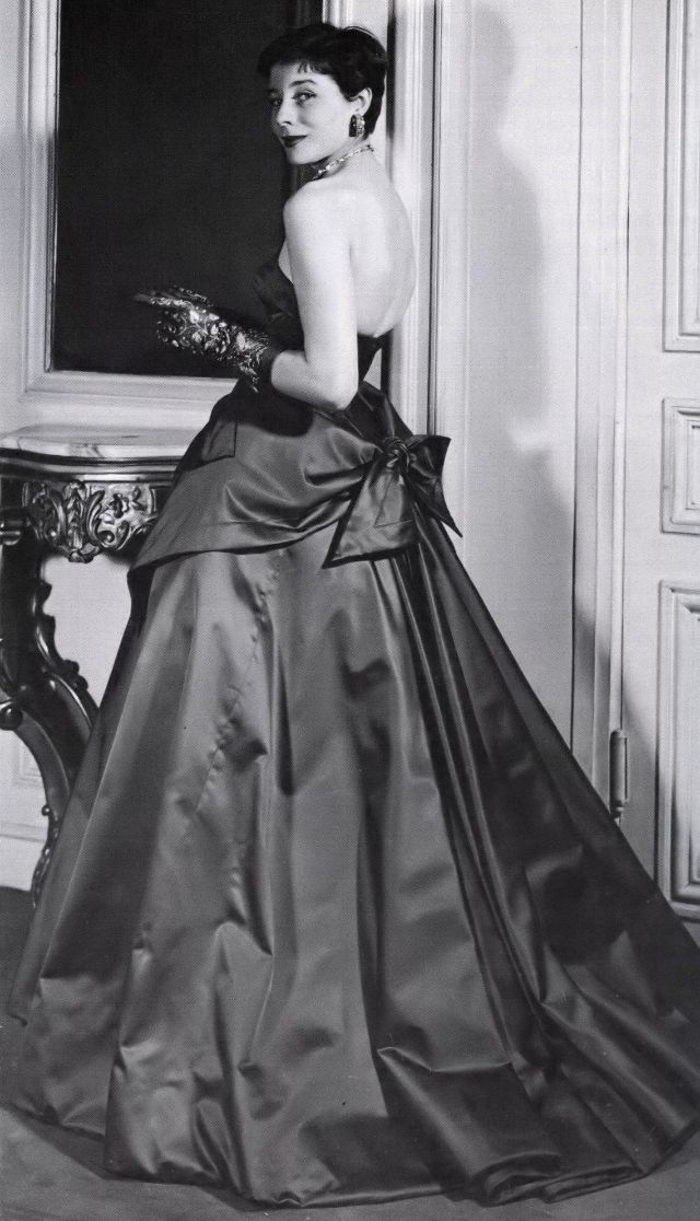 Bettina with her haircut 'a la Zizi Jeanmaire' is wearing satin evening gown with apron effect by Jacques Fath, 1950