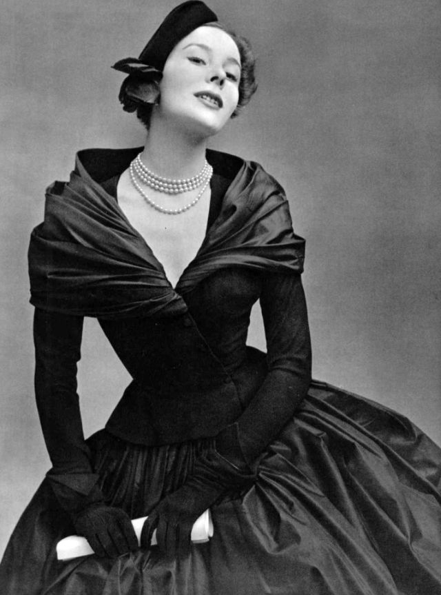 Bettina in dress of black matte wool bodice over black taffeta skirt and shawl, black cap with red rose completes the look by Christian Dior, 1951
