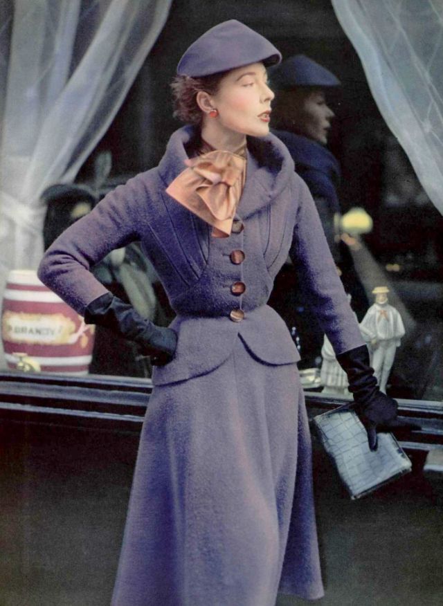 Bettina in violet wool suit, jacket is fitted with boldy notched lapel, skirt is bell shaped, blouse in tortoise shell silk by Paquin, 1951