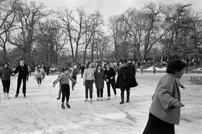 Skaters watched by a park guard on the frozen lake.