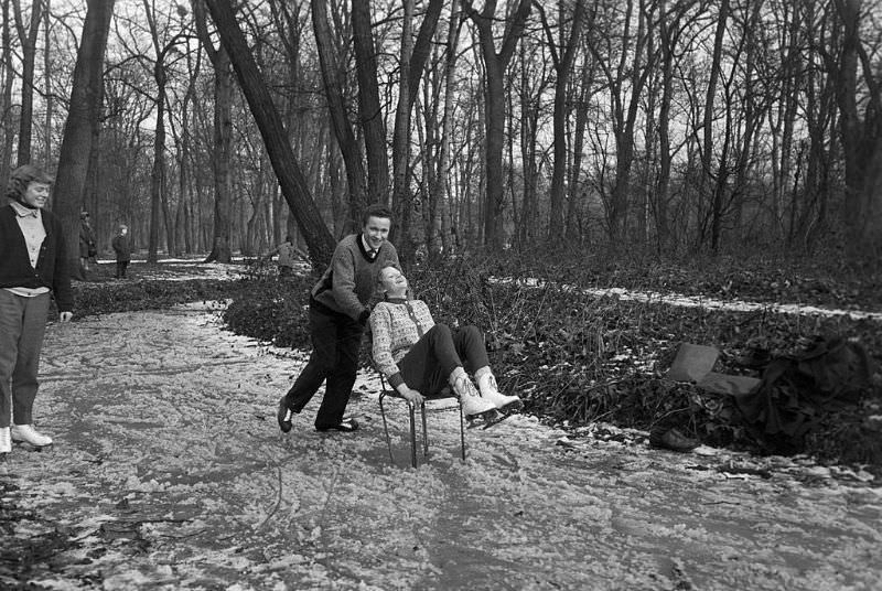 A young man pushing his friend on a chair on the frozen lake.