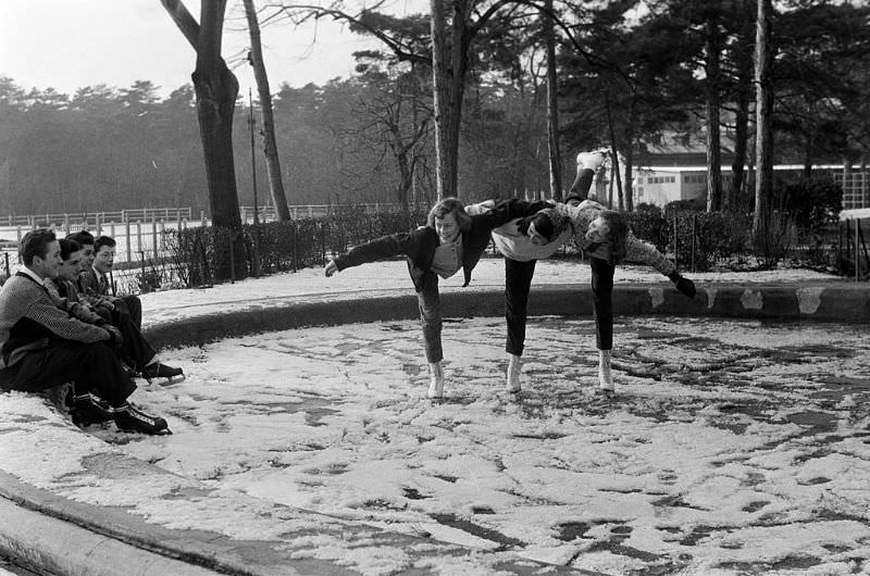 Three skaters doing tricks in front of their friends on the frozen lake.