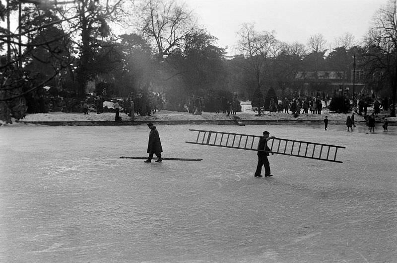 A guard and a worker carrying a ladder in the center of the lake.
