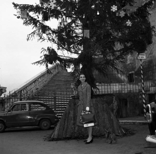 Audrey Hepburn standing in front of a huge Christmas tree while visiting Rome over the holidays, 1950.