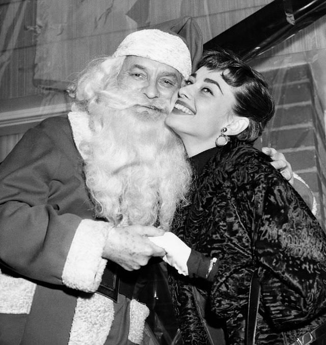 Audrey Hepburn smiles with Santa at a charity event in New York City during the holidays, 1953.