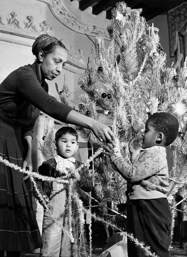 Josephine Baker trims her tree with her children in her French chateau, 1956.