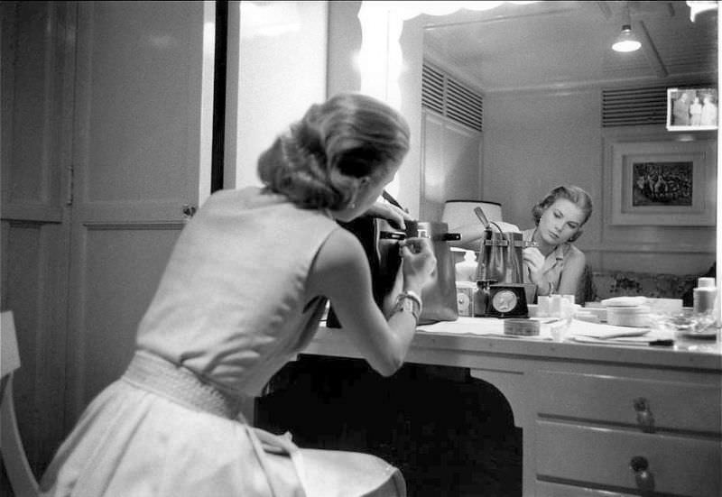 Grace Kelly in her dressing room adjusts her handbag by Hermès named for her (the Kelly bag), 1956