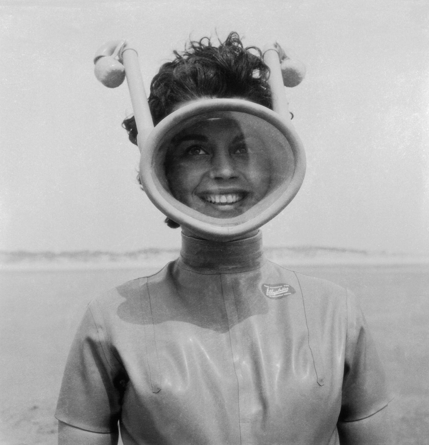 A woman equipped for a diving session with an unusual full face mask with integrated snorkels and water suit
