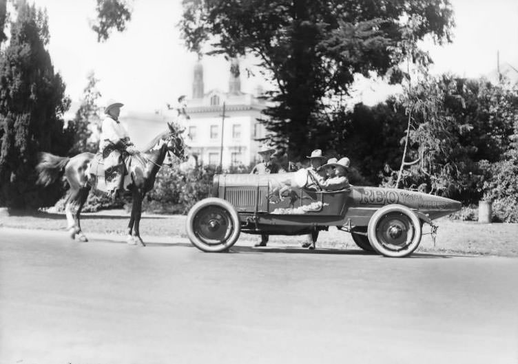REO Motor Car Company "Pony Express" promotional race car pictured alongside a cowboy sitting on a horse in San Francisco's Golden Gate Park, 1923