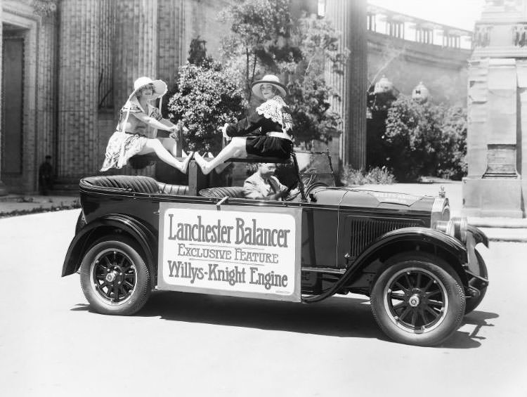 Two pretty girls balancing on a teeter-tooter inside a "Willy-Knight" convertible motor car promoting the "Lancaster Balancer" an exclusive feature of the Willys-Knight engine, 1925