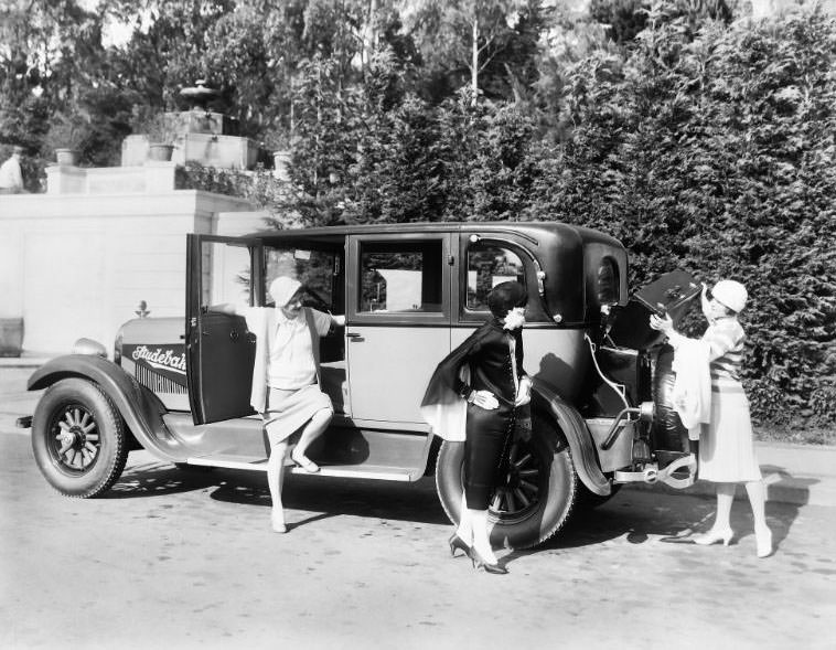 A Studebaker automobile pictured with a trio of beautiful woman including one seen loading her luggage into the trunk compartment. Photographed in San Francisco's St. Francis Wood neighborhood, circa 1926