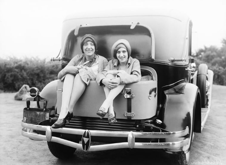 A pair of pretty ladies enjoying themselves while seated in the luggage compartment of a 1929 Hudson Motor Car in San Francisco, California, 1929
