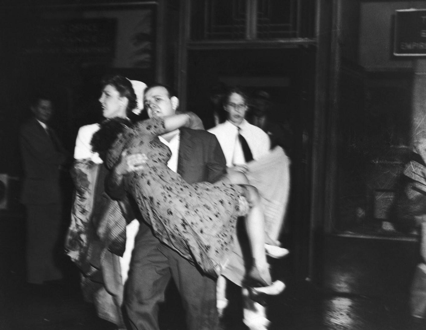 An injured woman is carried out of the Empire State Building to an ambulace on 34th Street, 1945