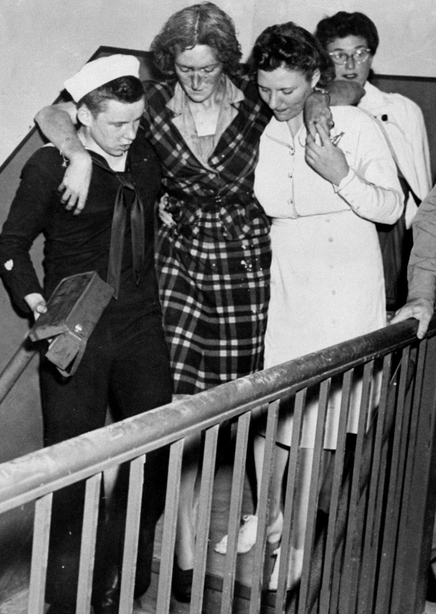 Don Maloney, Coast Guardsman, carries first aid kit as he helps injured woman down stairs at the Empire State Building after plane crashed into the building.