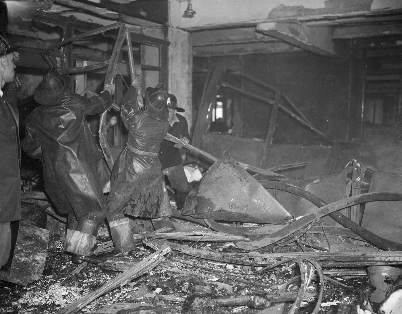 Firemen working amidst the wreckage from a plane which crashed in to the Empire State Building.