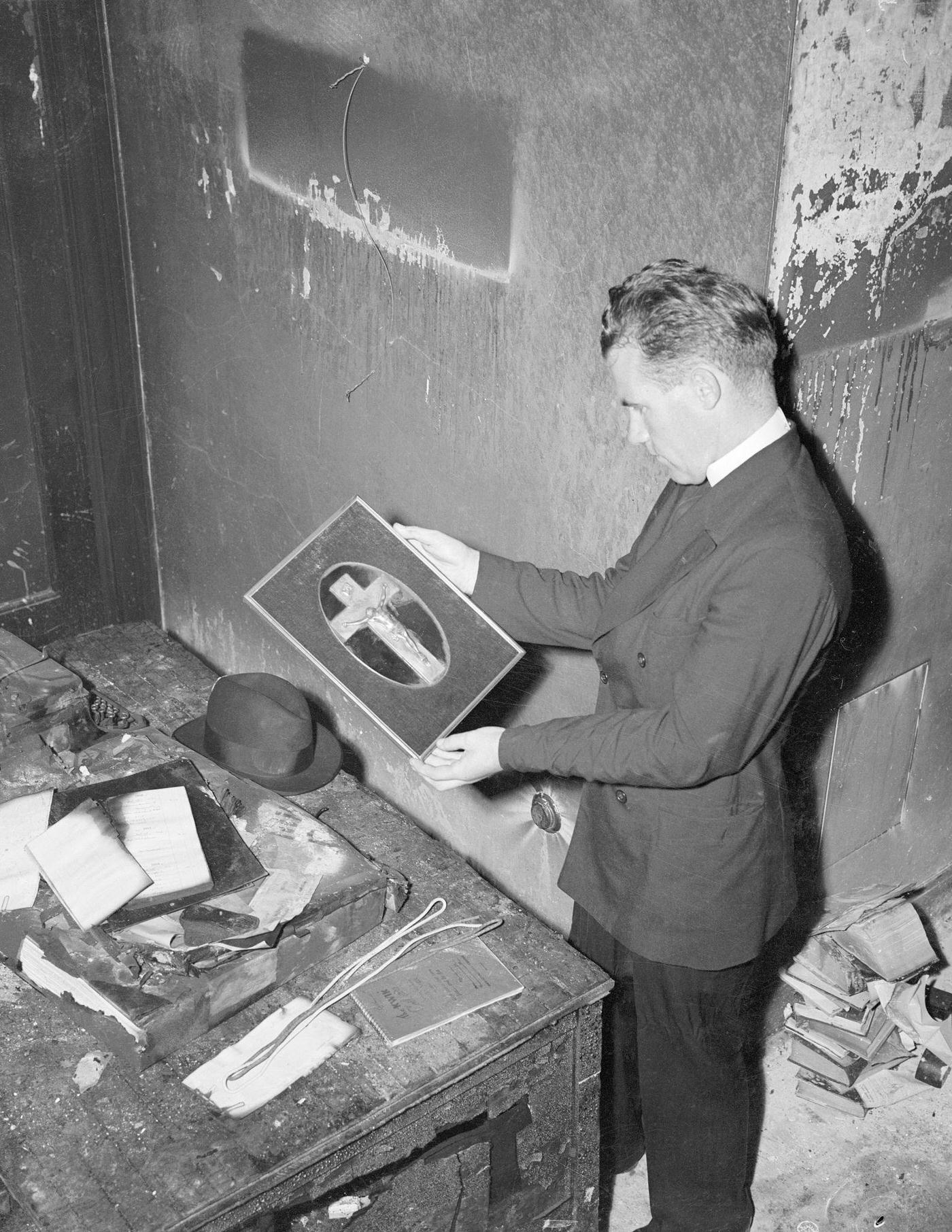 Empire State Building Plane Crash Story. Rev. M.S. Finneran of Montgomery, Alabama, looking at a small statue of Jesus on the cross, one of the few undamaged things on the 79th floor where the plane crashed.