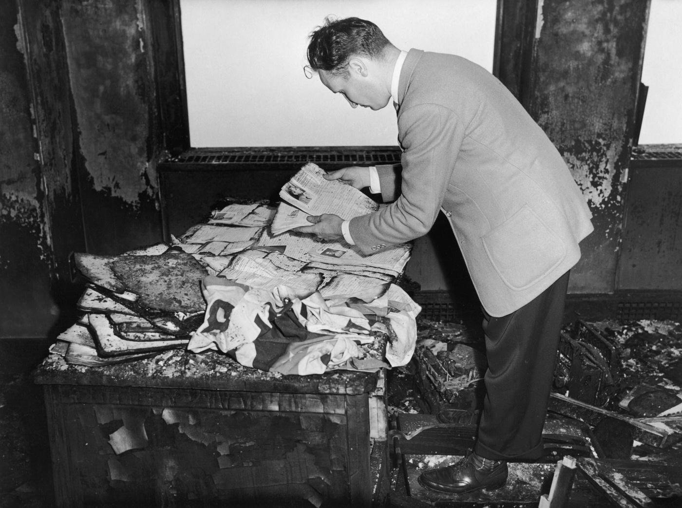 A man examines charred documents in an office in the Empire State Building after a B-25 Mitchell bomber