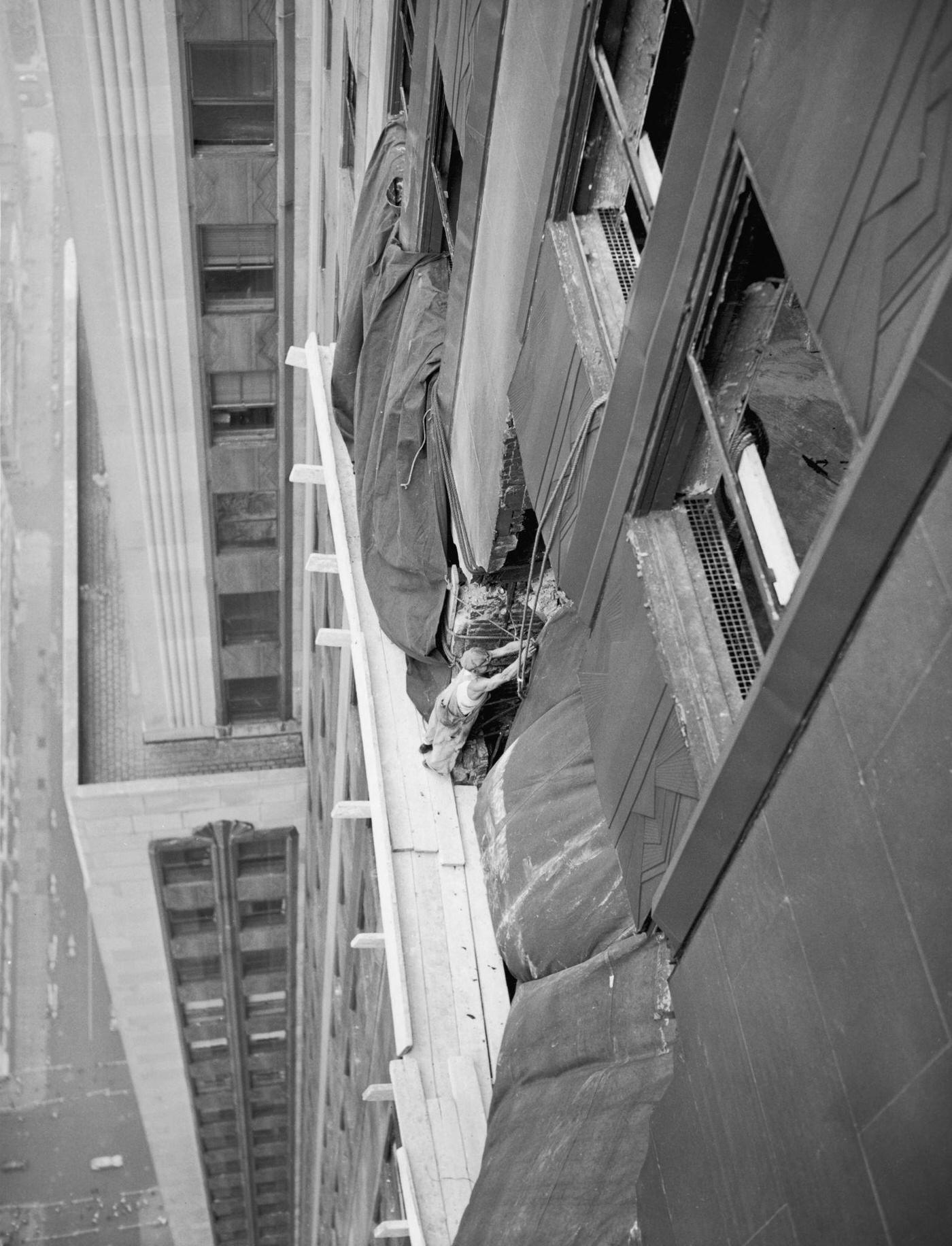 A workman fixing tarpaulins over broken windows at the Empire State Building, 1945