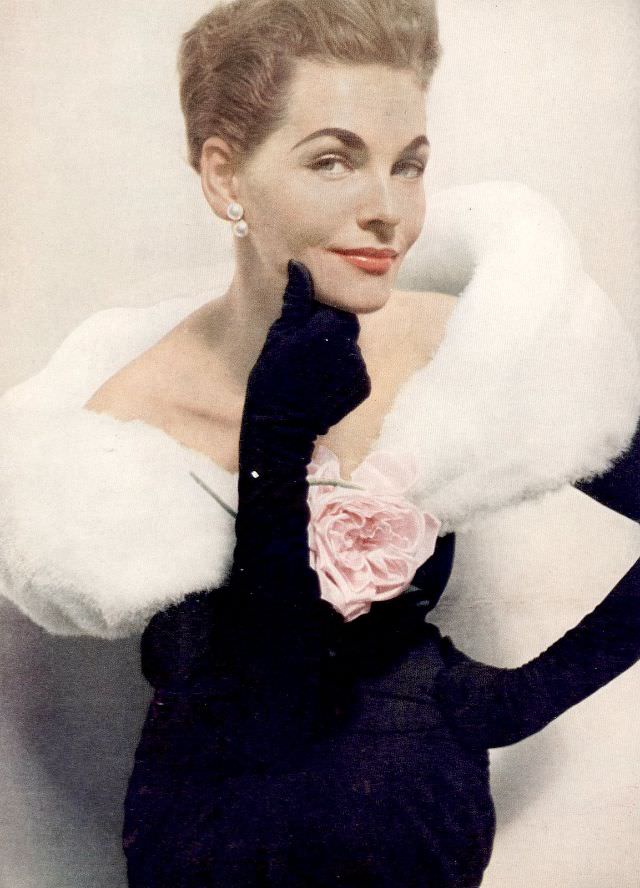 Georgia Hamilton is wearing black sheath with white down fichu held with pink rose by Balenciaga, Harper's Bazaar, December 1953
