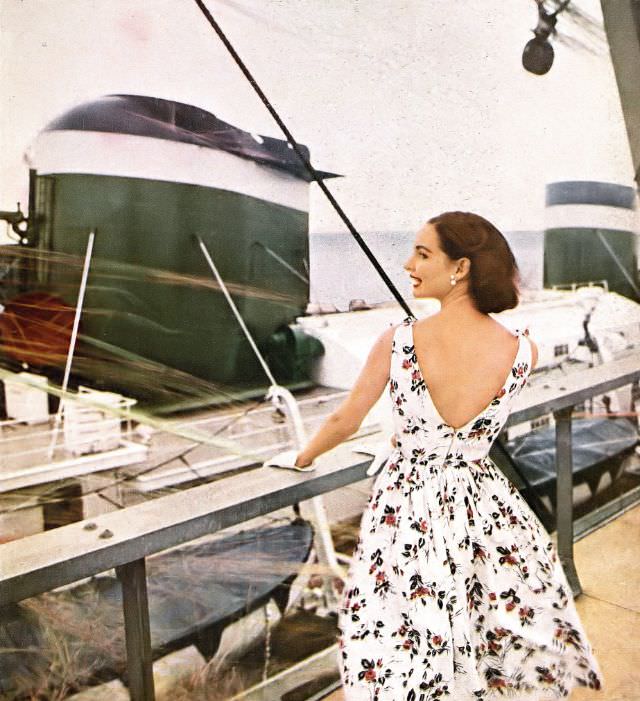 Cherry Nelms in bare-backed white piqué sundress printed with roses, by Alex Colman, photo by Gleb Derujinsky aboard Grace Lines' Santa Paula, Harper's Bazaar, January 1956