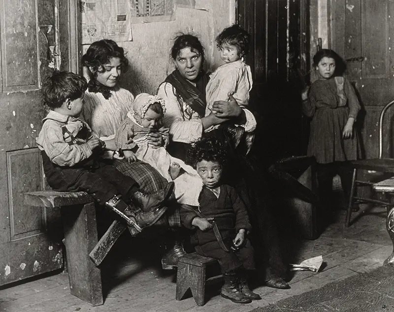 Italian family sits for its portrait in Chicago tenement near Hull House, 1910.