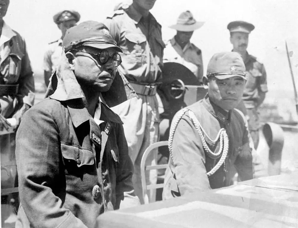 Kaida Tatsuichi, commander of the Japanese 4th Tank Regiment, and his chief of staff Shoji Minoru listen to the terms of surrender on HMAS Moresby at Timor.