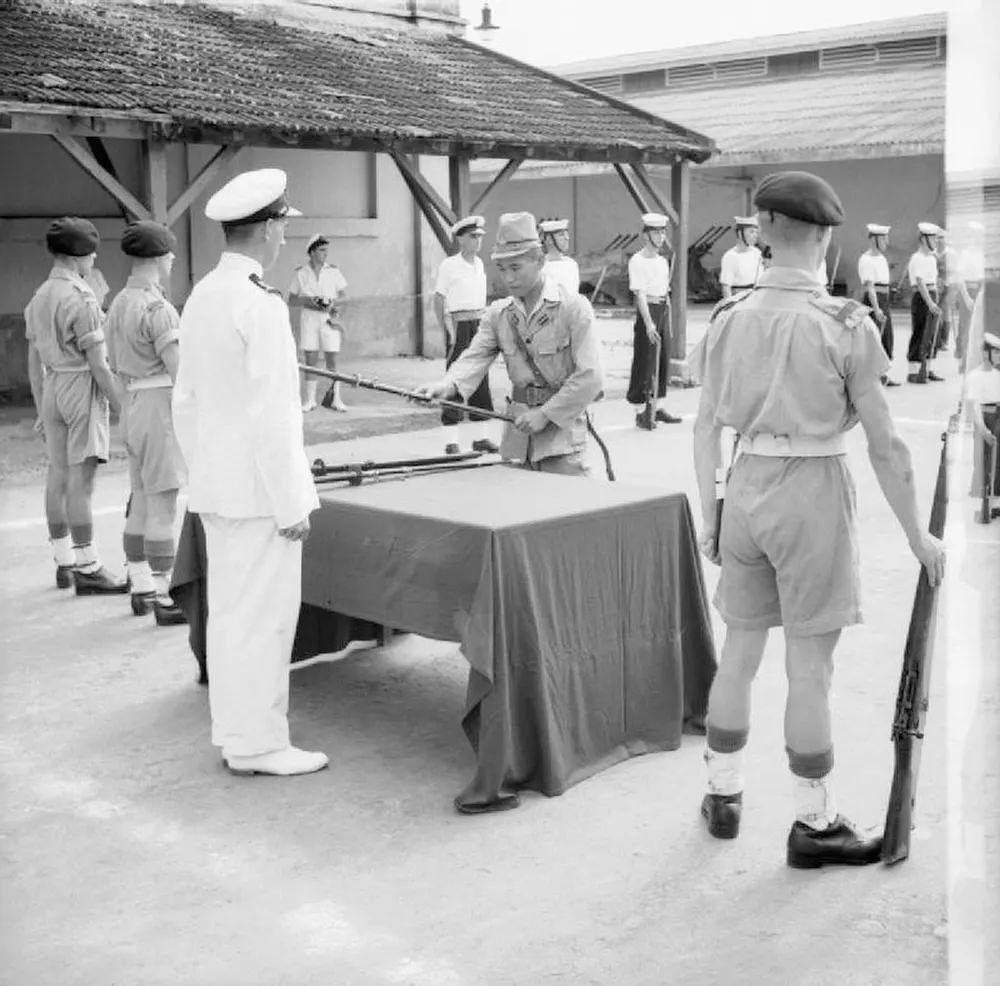 A Japanese officer surrenders his sword to a British Lieutenant in a ceremony in Saigon, French Indochina.