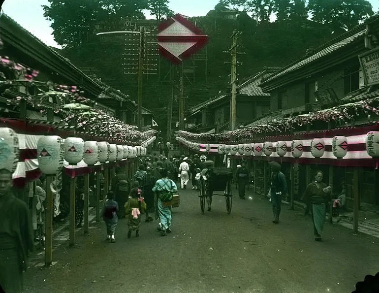 Crowd-filled street lined with banners and lanterns.