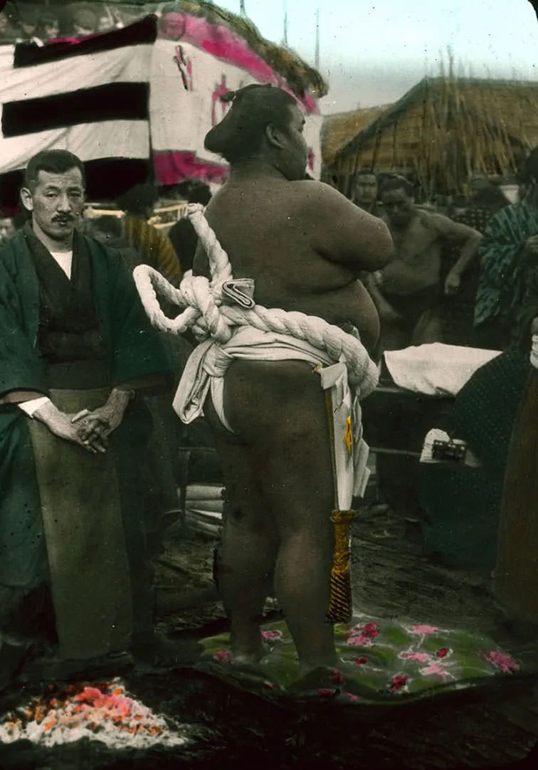 Men preparing for sumo wrestling outdoors.