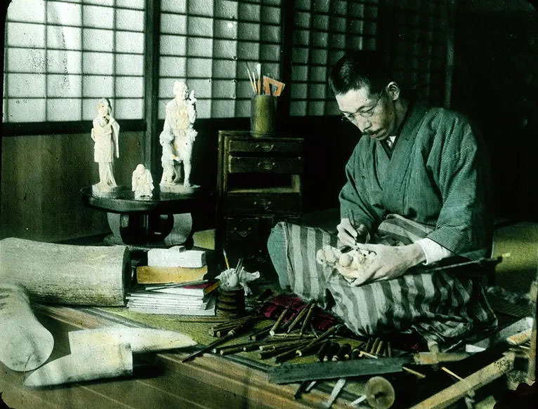 Man carving ivory statue of mother and child.