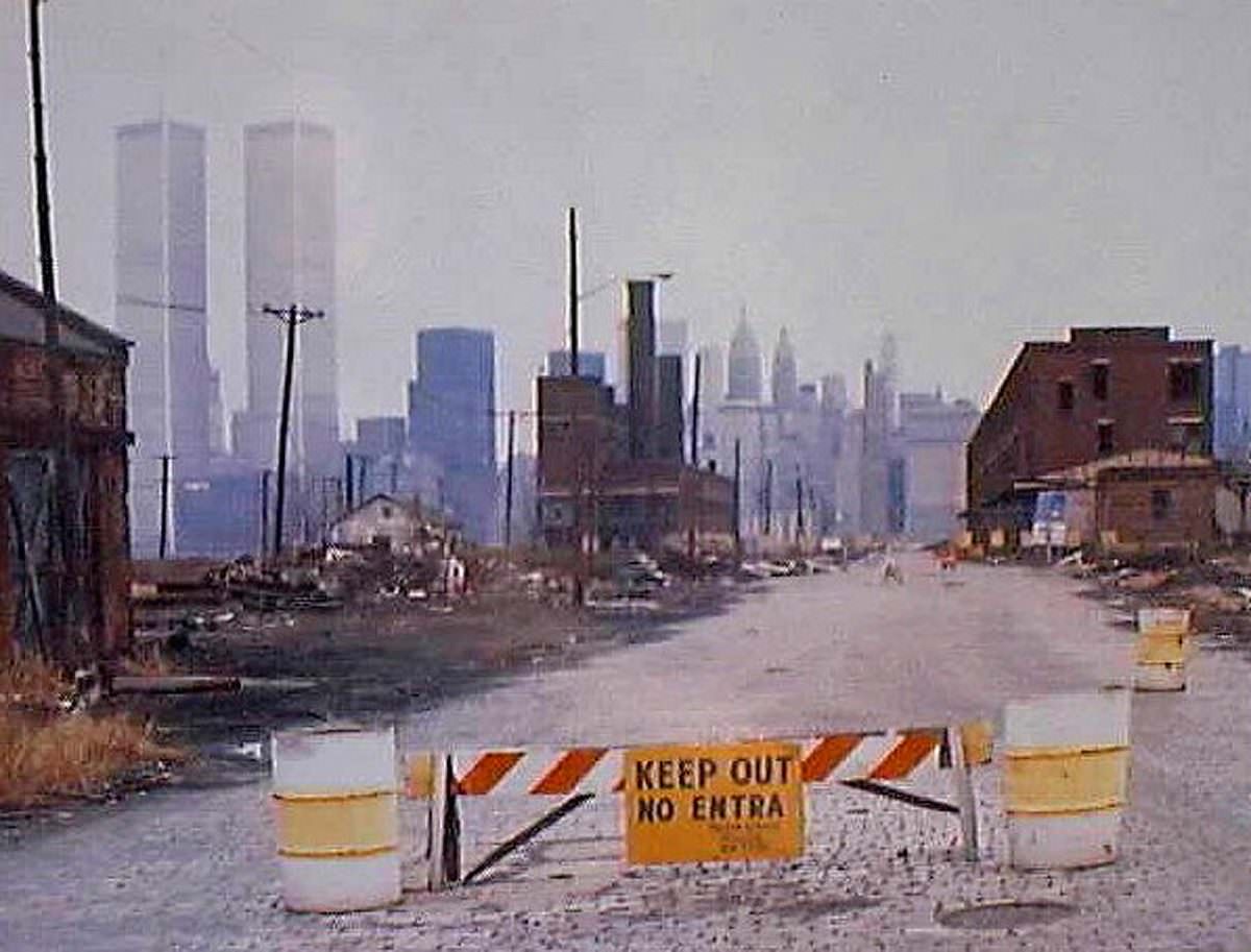 The World Trade Center and Lower Manhattan hover across the Hudson, Jersey City, March 1976.