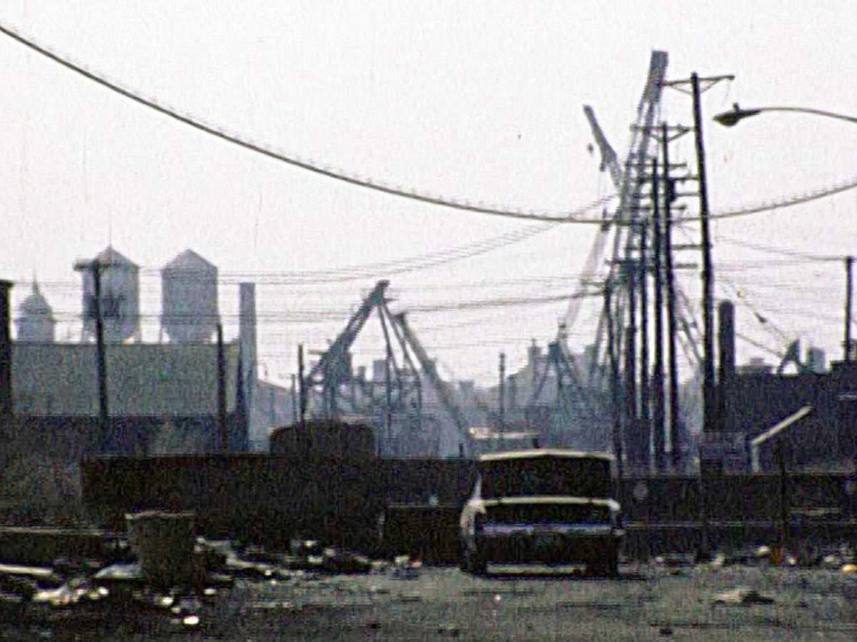 Two water towers on top of Ellis Island. Trash and a stripped abandoned car by the Morris Canal small basin, Jersey City, April 1976