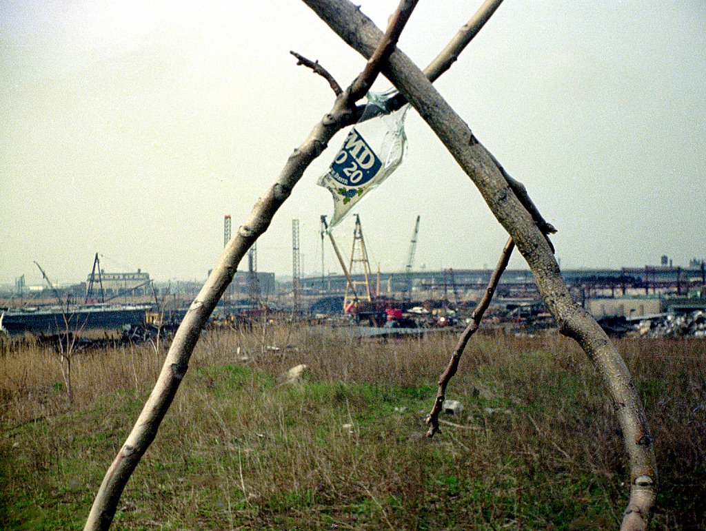 Abandoned cranes, barge at left, industrial wasteland, and old Jersey Central railroad facility in the distance at left,Jersey City, 1975