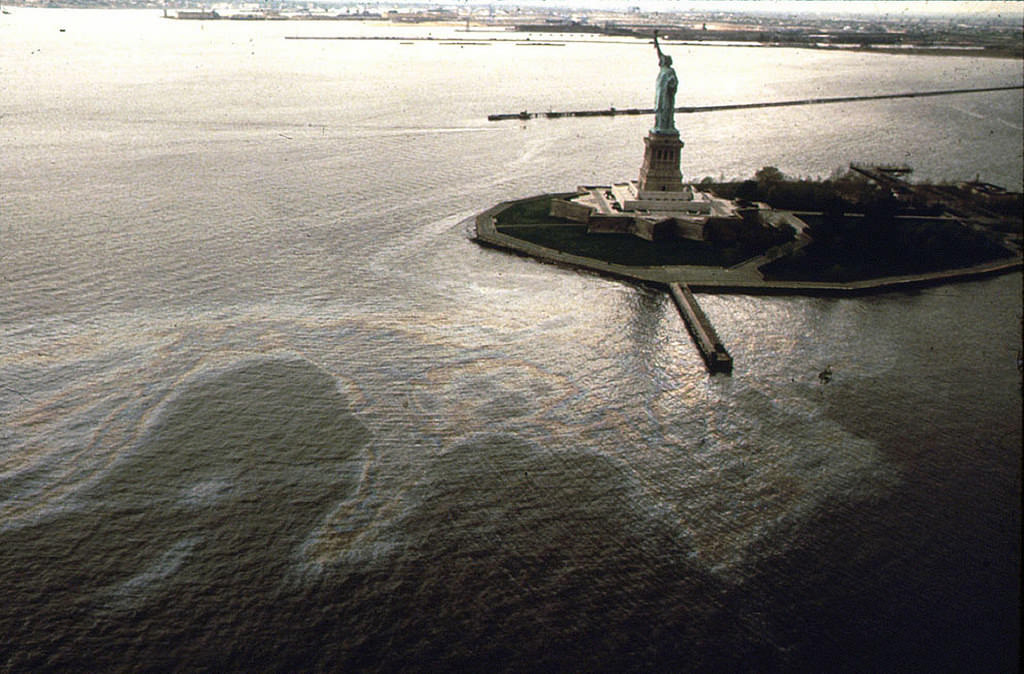Large pool of gasoline swirls around the Statue of Liberty from a ruptured pipeline at the Exxon facility near Black Tom and Caven Point in Jersey City, June 1972
