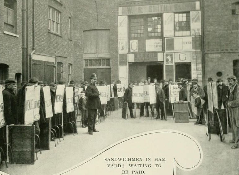 Sandwich men waiting to be paid in Ham Yard in Soho.