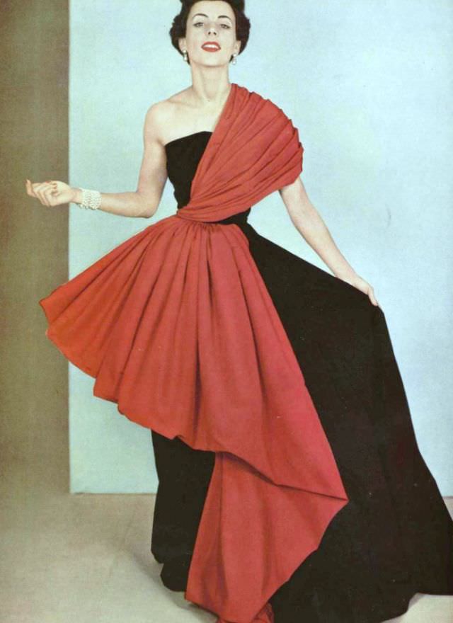 Model in intricately draped red faille on black faille gown by Grès, 1950