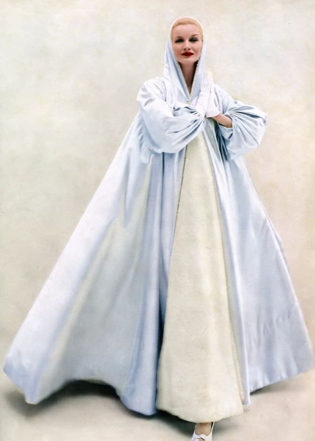 Sunny Hartnett in a billowing hooded evening coat of ice blue satin by Grès, 1954