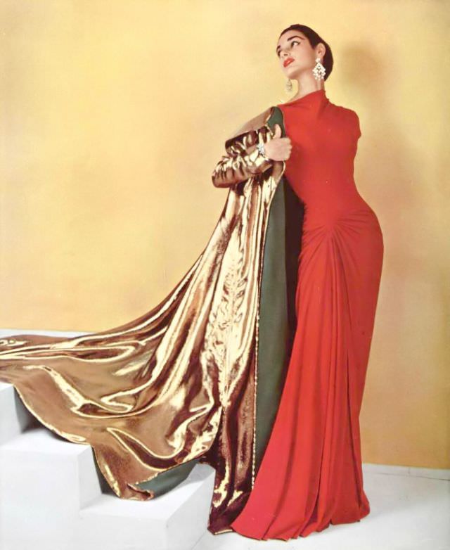 Jacky Mazel in figure-hugging coral silk-jersey evening dress worn with gold lamé evening coat by Grès, chandelier earrings by Scémama, 1955