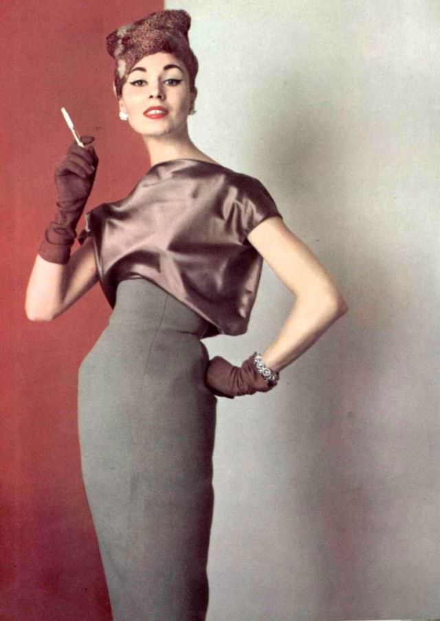 Model in elegant understated gray wool dress with satin blouson bodice by Grès, hat by Svend, 1956