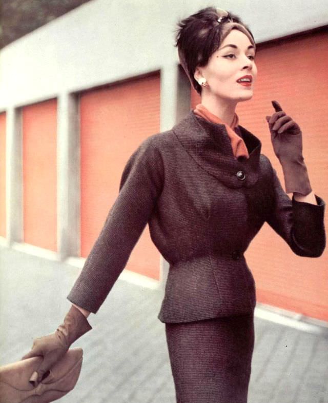 Model in fine wool checked suit, jacket has expanded bust and flexible back, worn over jersey blouse, by Grès, hat by Legroux, clutch by Muth, 1956