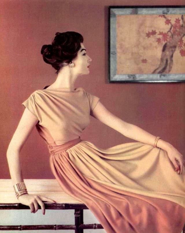 Simone d'Aillencourt in beige and orange jersey dress, bodice is gathered at the shoulders and buttoned belt holds pleats in front, by Grès, 1957