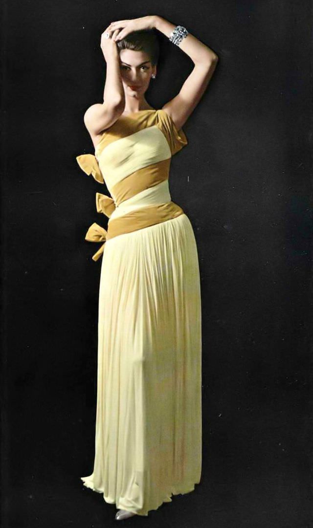 Simone d'Aillencourt in fluid one-shoulder mousseline jersey gown banded and tied in bows of velvet by Grès, jewelry by Scémama, 1957