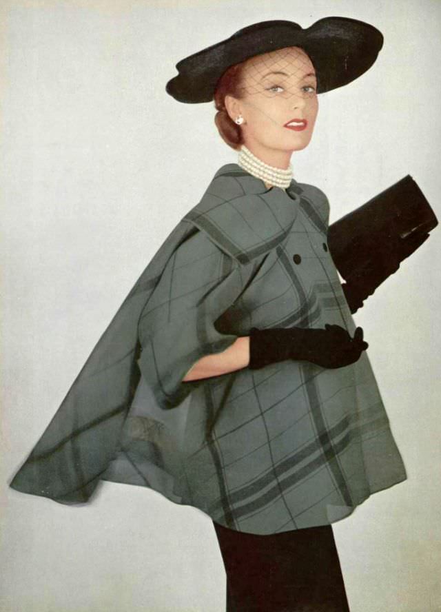 Model in figure-hugging black dress worn with light sheer organza plaid jacket by Grés, hat by Gilbert Orcel, 1951