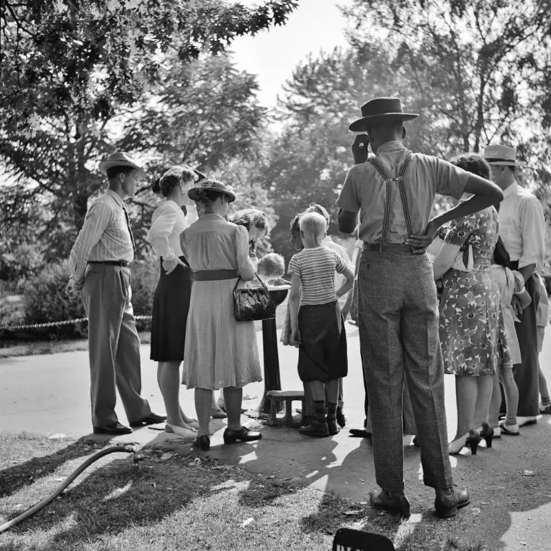 Group waiting to drink water out of a public fountain in the zoological park, Detroit, Michigan, July 1942.
