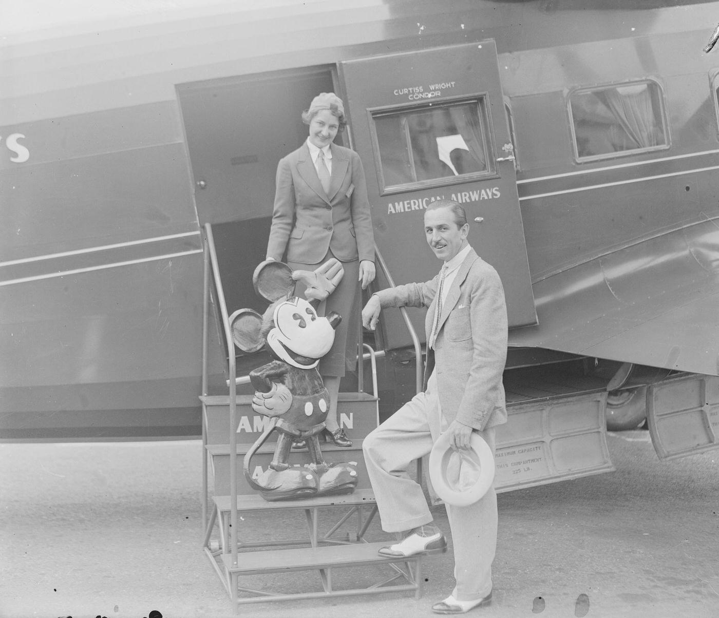 Stewardess Izola Readle takes tickets from cartoonist Walt Disney, with his creation Mickey Mouse, in Newark, New Jersey