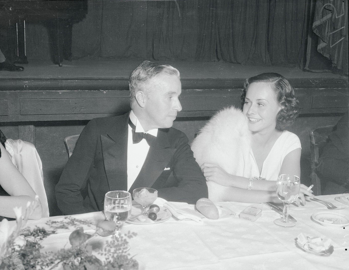 Charlie Chaplin and Paulette Goddard enjoy their little joke as they attend the party given in honor of Walt Disney